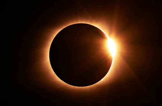 Eclipse solar total en el momento del efecto anillo de diamantes, con la luna cubriendo el disco solar y un destello de luz radiante.